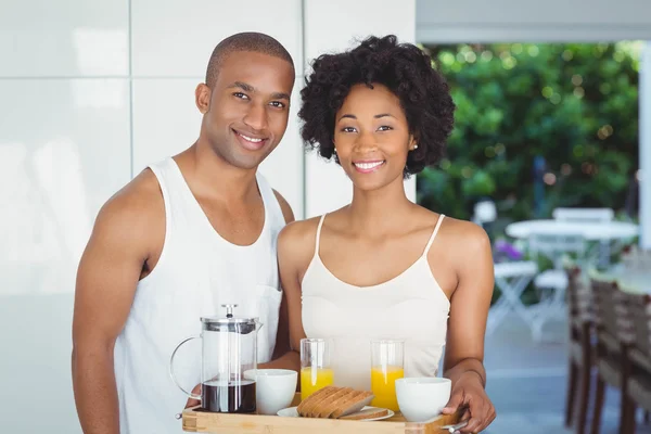 Happy couple holding breakfast tray in the kitchen — Stok fotoğraf