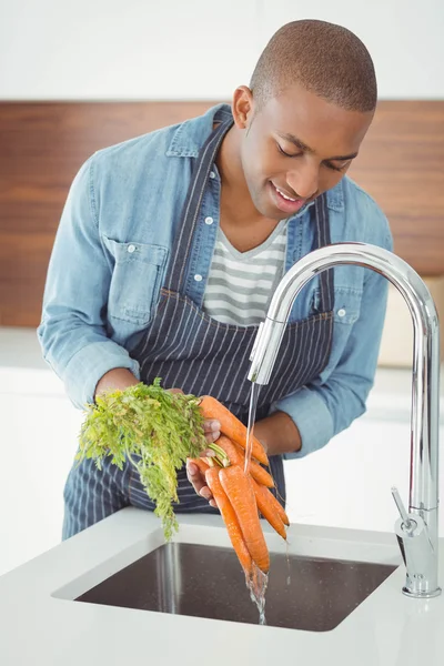 Handsome man washing carrots — Stockfoto