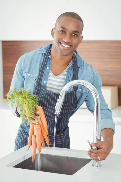 Handsome man washing carrots — Stockfoto