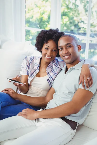 Happy couple using smartphone on the sofa — Stock Photo, Image