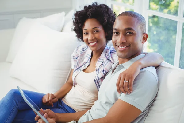 Pareja feliz usando la tableta en el sofá — Foto de Stock