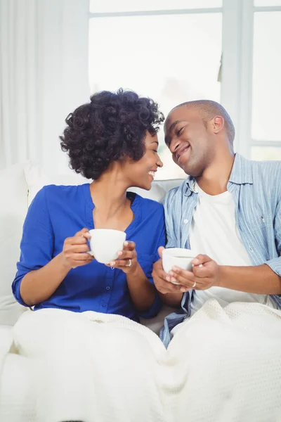 Happy couple holding cups on the sofa — 图库照片