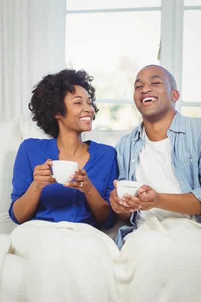 Casal feliz segurando copos no sofá — Fotografia de Stock