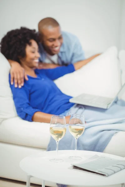 Pareja feliz en el sofá usando el ordenador portátil —  Fotos de Stock