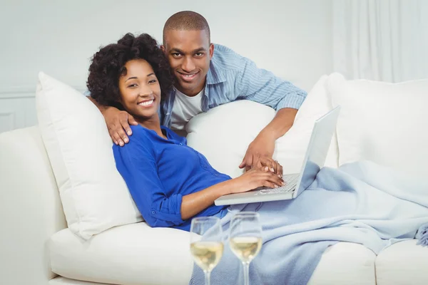 Happy couple on the sofa using laptop — Zdjęcie stockowe