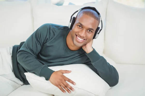 Handsome man lying on the sofa with headphones — Stock Photo, Image