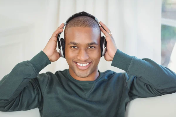 Homem sorridente com fones de ouvido no sofá — Fotografia de Stock