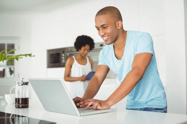 Bello uomo che utilizza il computer portatile in cucina — Foto Stock