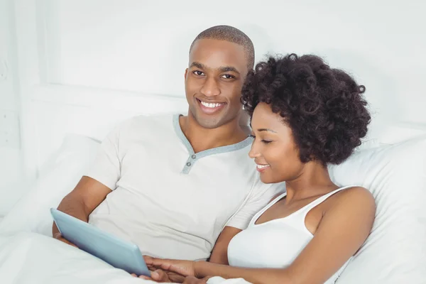 Smiling couple at bed using tablet — Stok fotoğraf