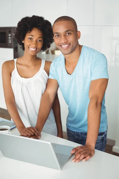 Couple souriant utilisant un ordinateur portable dans la cuisine — Photo