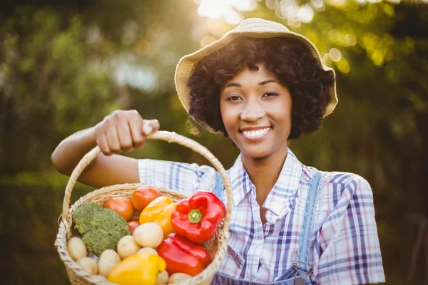 Smiling woman showing a basket of vegetables — 图库照片