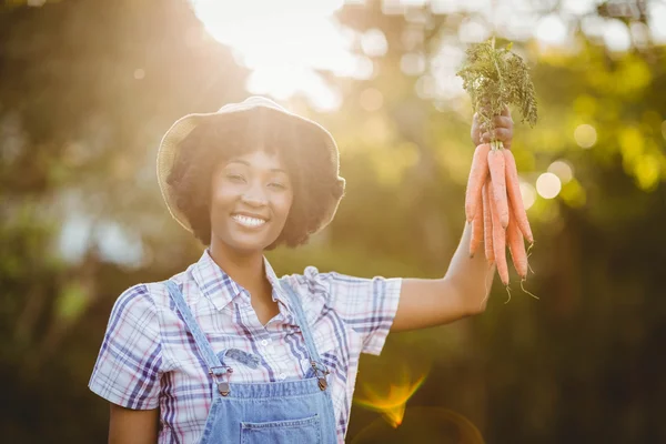 Smiling woman holding carrots — Stockfoto