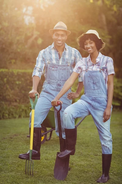 Smiling couple holding shovel and rake — Stok fotoğraf