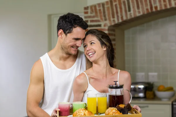 Happy couple holding a tray of breakfast — Zdjęcie stockowe