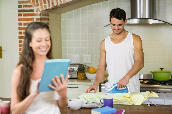 Homem engomando uma camisa na cozinha — Fotografia de Stock