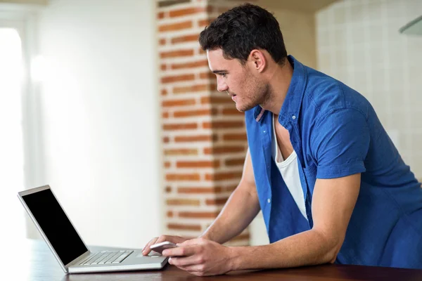 Giovane uomo che utilizza il computer portatile in cucina — Foto Stock