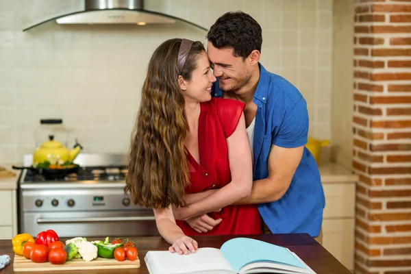 Couple embracing while checking the recipe book — Stok fotoğraf