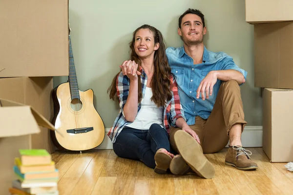 Young couple sitting together on the floor and smiling — Stock Photo, Image