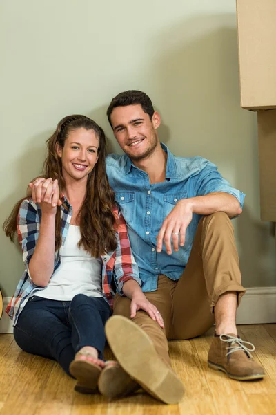 Jovem casal sentado no chão e sorrindo — Fotografia de Stock