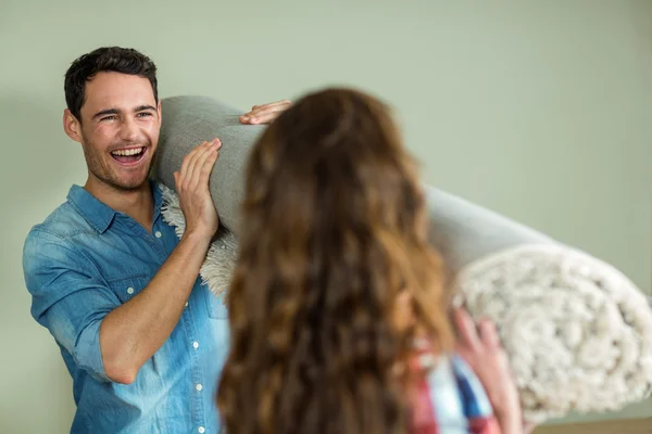 Happy couple carrying rolled up rug — Stock Photo, Image