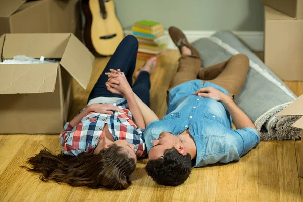 一对年轻夫妇躺在新房子的地板上 — 图库照片