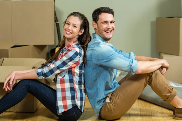 Young couple sitting back to back in their house — Stok fotoğraf