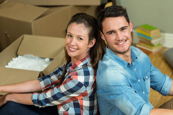 Young couple sitting back to back in their new house — Stock Photo, Image