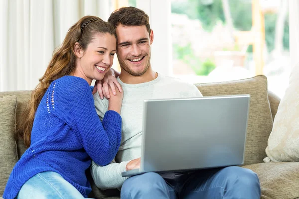 Junges Paar sitzt auf Sofa und benutzt Laptop — Stockfoto