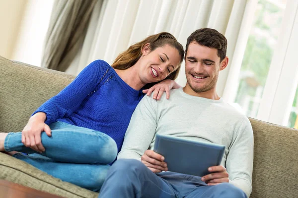坐在沙发上使用数码平板电脑的年轻夫妇 — 图库照片
