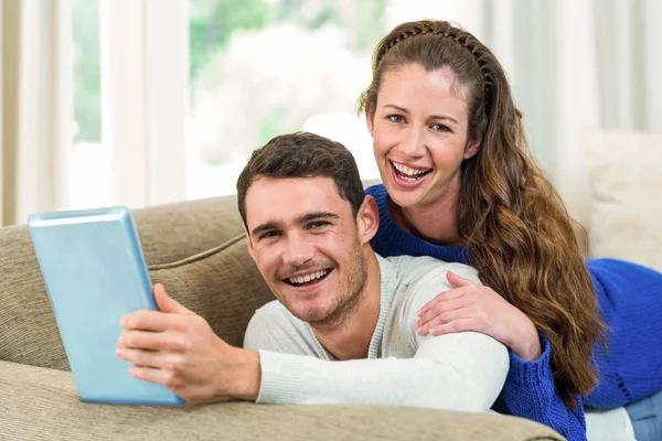 Jovem casal sentado no sofá e usando tablet digital — Fotografia de Stock