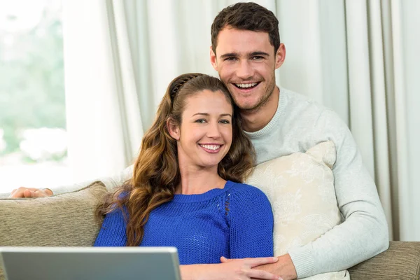 Junges Paar sitzt auf Sofa und benutzt Laptop — Stockfoto