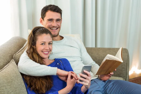 Jeune couple assis sur le canapé et utilisant un téléphone mobile — Photo