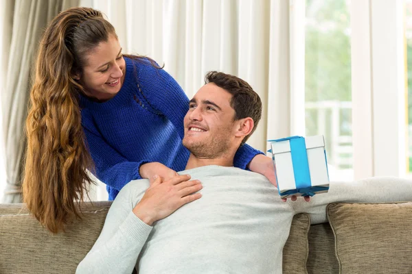 Woman giving a surprise gift to her man — Stockfoto