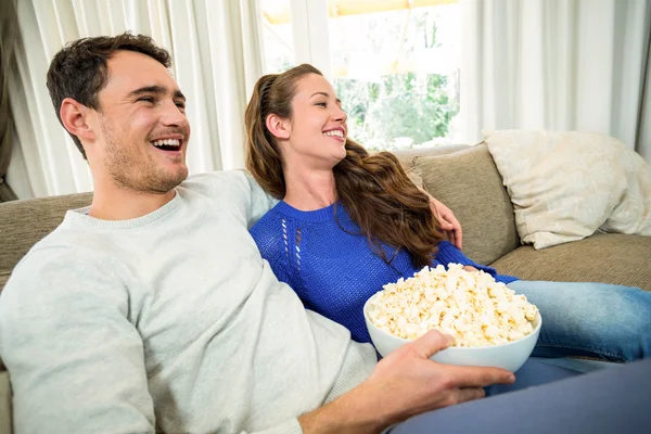 Молодая пара ест попкорн во время просмотра телевизора — стоковое фото