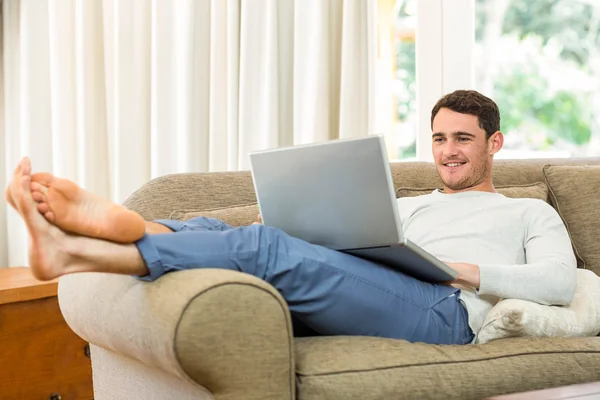 Mężczyzna korzystający z laptopa na kanapie — Zdjęcie stockowe