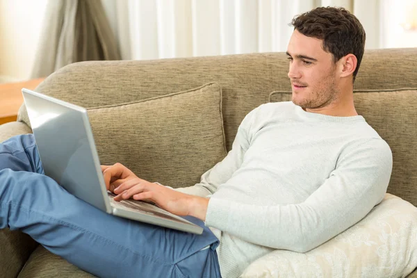 Mann benutzt Laptop auf Sofa — Stockfoto