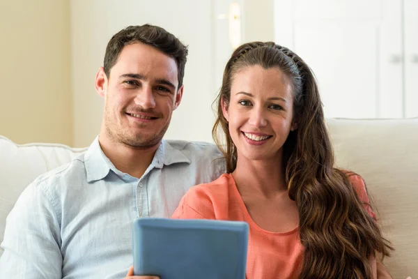 Young couple using digital tablet on sofa — Stok fotoğraf