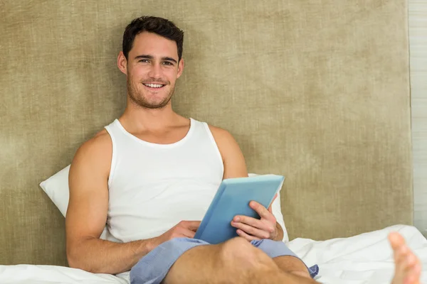 Young man using a digital tablet in bedroom — Stok fotoğraf