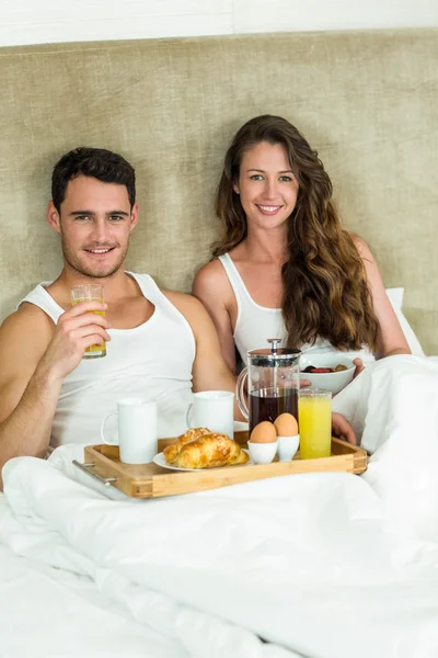 Jovem casal tomando café da manhã na cama — Fotografia de Stock