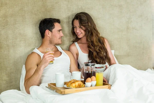 Jovem casal tomando café da manhã na cama — Fotografia de Stock