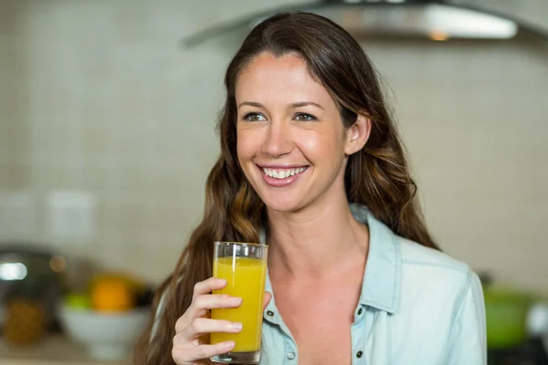 Jovem mulher sorrindo enquanto bebe suco — Fotografia de Stock