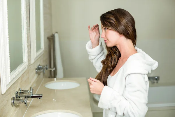 Hermosa mujer mirando en el espejo del baño —  Fotos de Stock