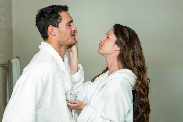 Mujer aplicando crema hidratante en el hombre — Foto de Stock