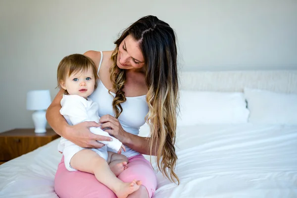 Mulher morena segurando um bebê em uma cama — Fotografia de Stock