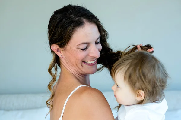 Oynak bir bebek tutan gülümseyen esmer kadın — Stok fotoğraf