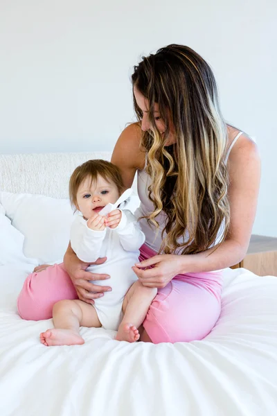 Bebê bonito brincando com um pente em um colo de mulher — Fotografia de Stock