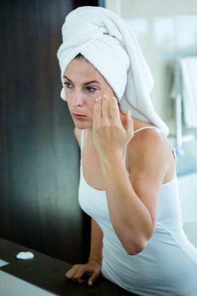 Vrouw toepassen gezichtscrème in de spiegel — Stockfoto