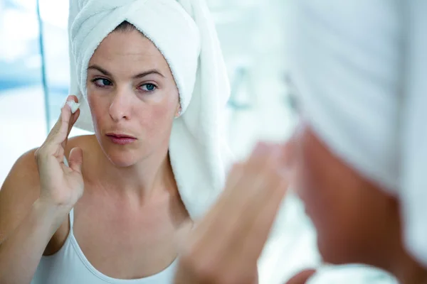 Mulher aplicando creme facial no espelho — Fotografia de Stock