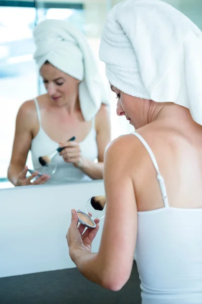 Woman applying face powder in the bathroom mirror — Stock Photo, Image