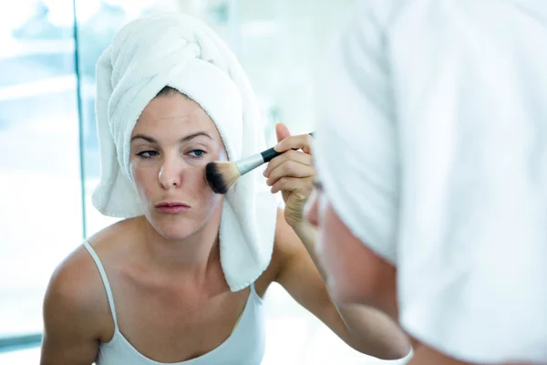 Mulher aplicando pó facial no espelho do banheiro — Fotografia de Stock